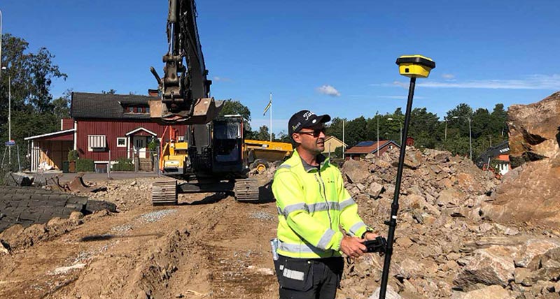 Leica iCON smart antenna used on construction site with a digger and a red house in the background